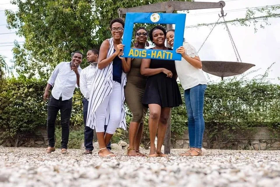 Six membres d'ADIS-HAÏTI posent en plein air derrière le cadre photo bleu ADIS-HAÏTI