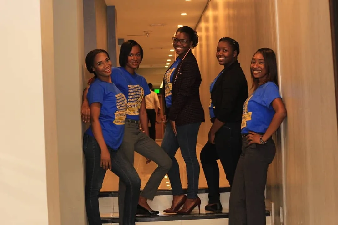 Cinq membres d'ADIS-HAÏTI en t-shirt bleu ARSHOEA posent dans le hall d'un hôtel