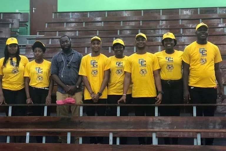 Une délégation d'ADIS-HAÏTI en t-shirts et casquettes jaunes, alignée dans un amphithéâtre