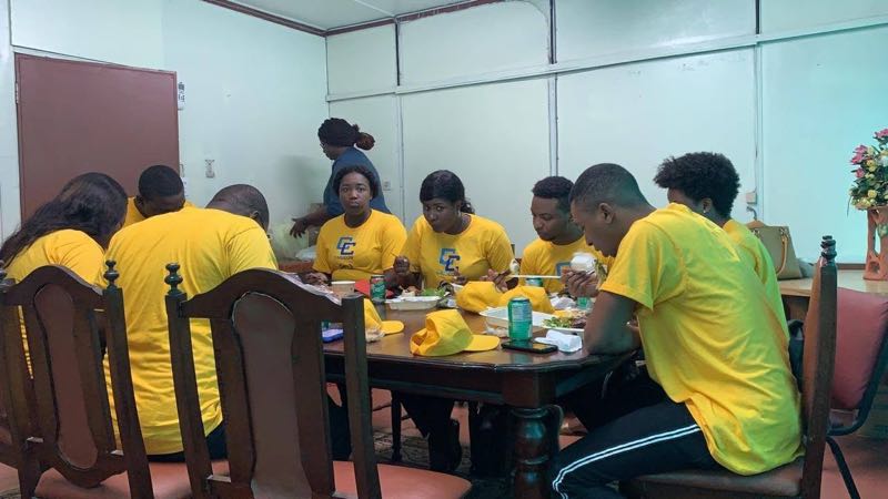 Repas de groupe en tenue jaune lors d'un voyage CARICOM