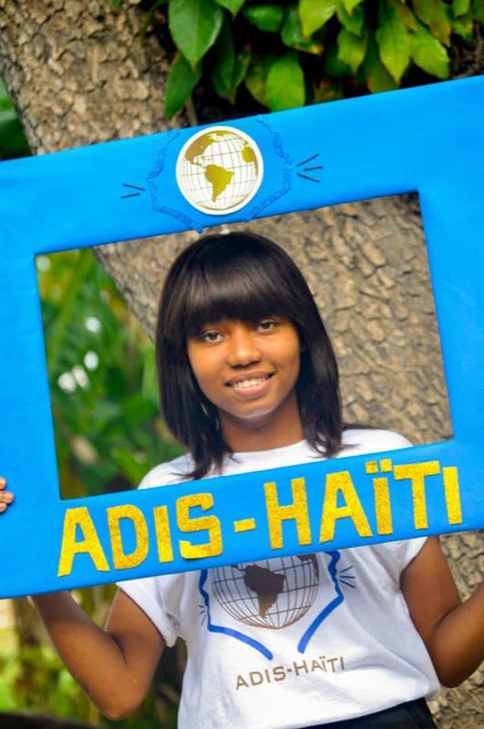Jeune membre d'ADIS-HAÏTI posant avec le cadre photo de l'organisation