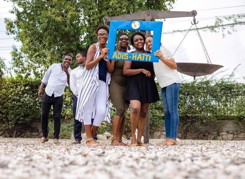 Groupe de membres d'ADIS-HAÏTI avec le cadre photo, sculpture en fond
