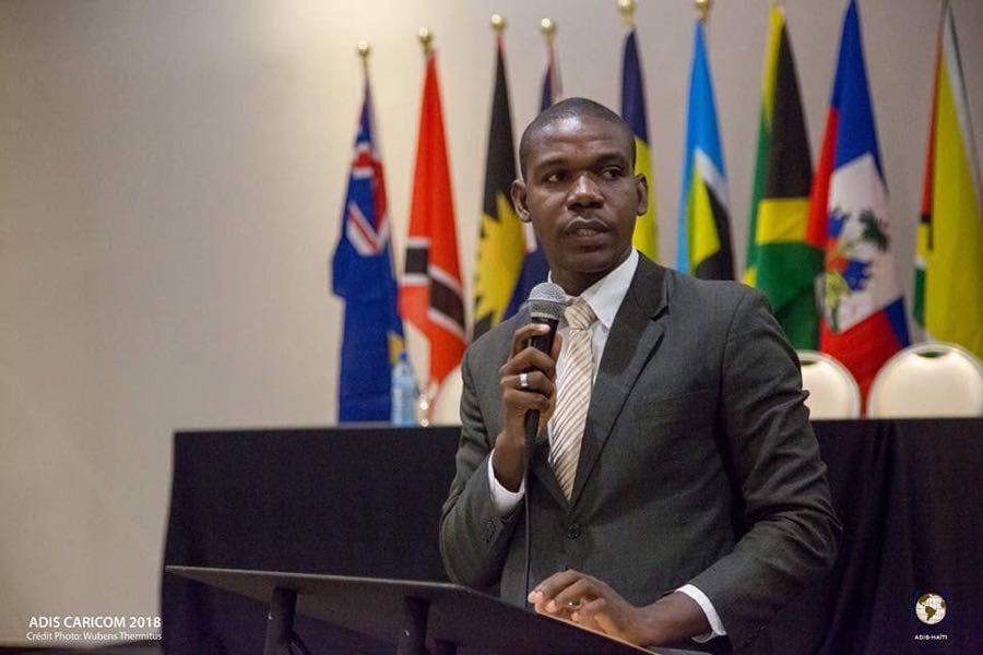 Intervenant au podium devant les drapeaux des pays de la CARICOM, cours sur le repositionnement d'Haïti à la CARICOM